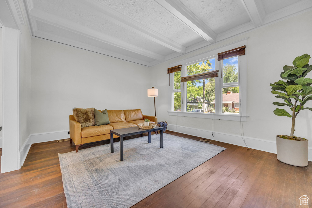 Living area featuring beamed ceiling, dark wood-style flooring, and baseboards