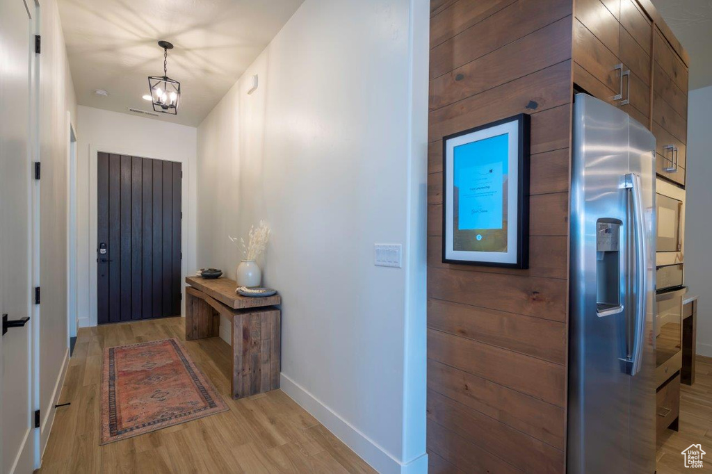 Foyer with baseboards, light wood-type flooring, and a chandelier