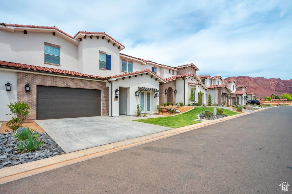 Mediterranean / spanish-style home with an attached garage, a tiled roof, stucco siding, concrete driveway, and a mountain view