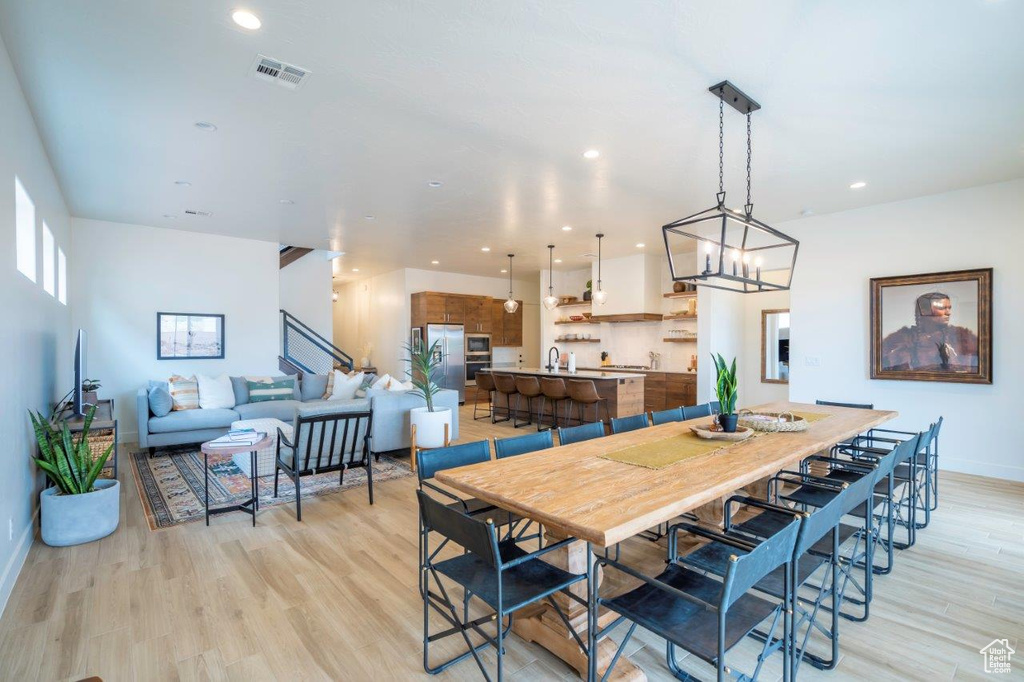 Dining space with light wood-style flooring, a chandelier, baseboards, recessed lighting, and stairway