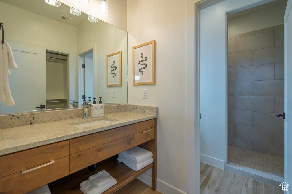 Bathroom with vanity, baseboards, wood finished floors, and walk in shower