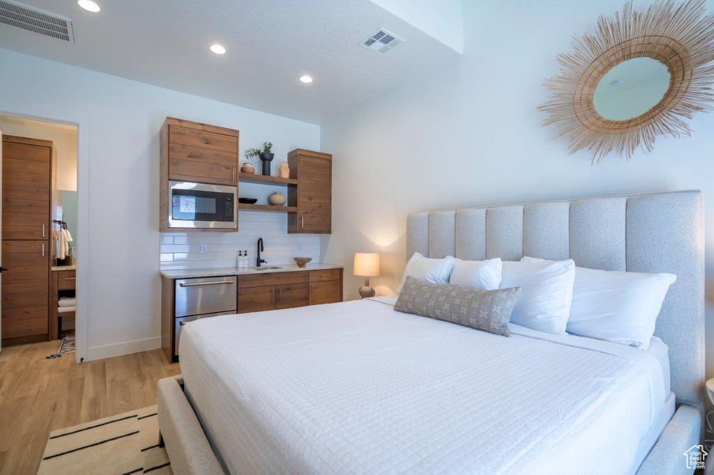 Bedroom with light wood finished floors, recessed lighting, a sink, and baseboards