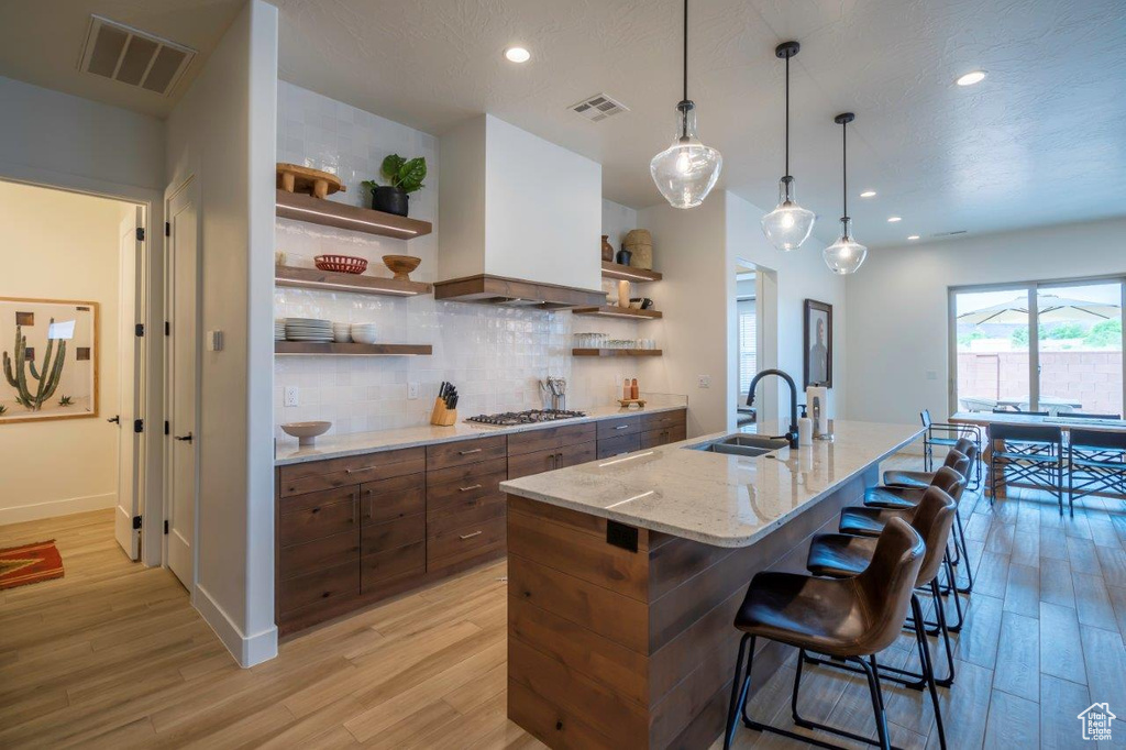 Kitchen featuring open shelves, a sink, light wood-type flooring, and recessed lighting