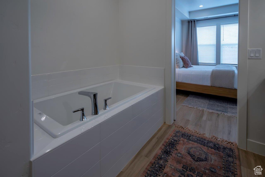 Ensuite bathroom featuring a bath and wood finished floors