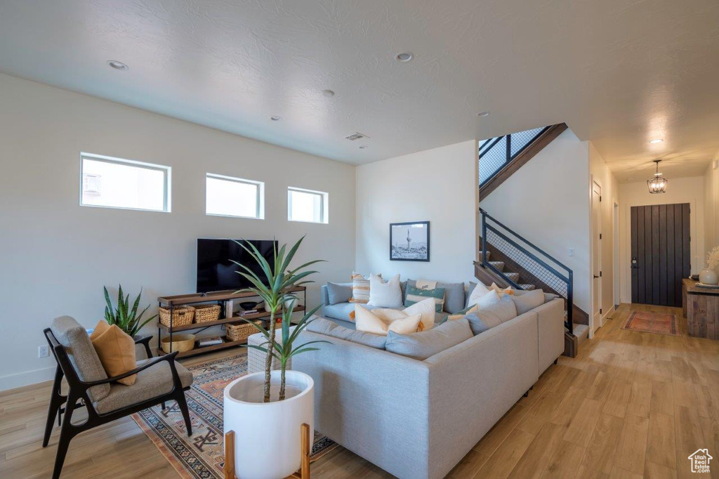 Living room with light wood-style floors, stairway, and baseboards