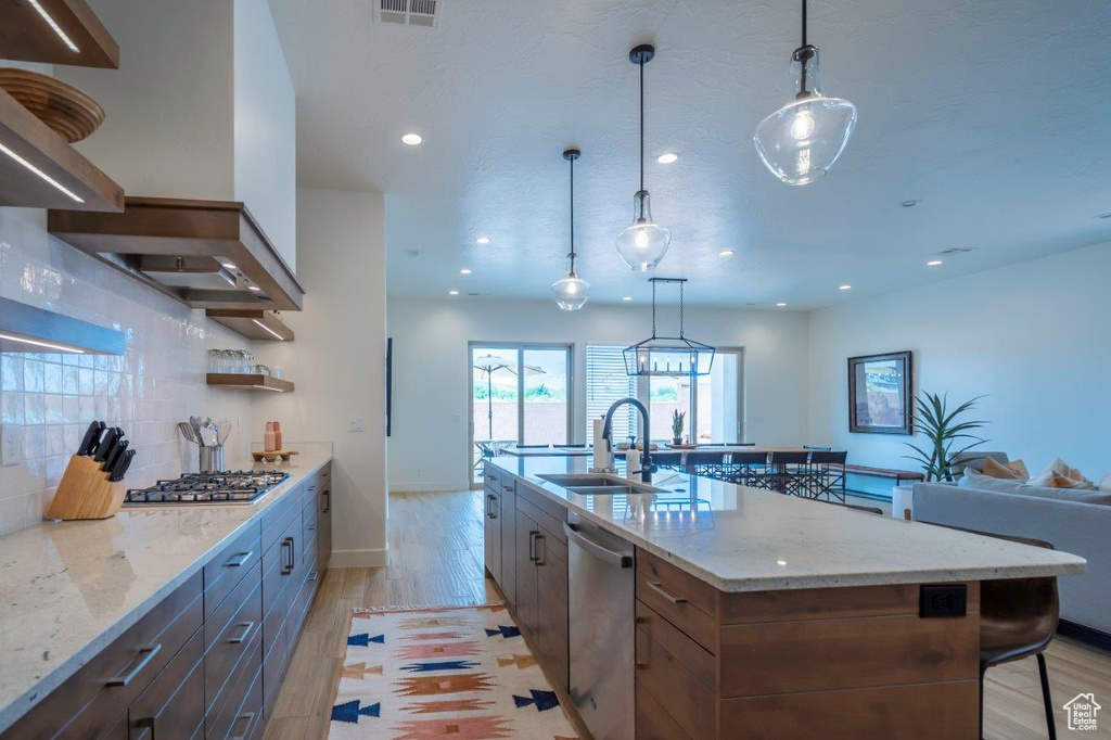 Kitchen with a sink, stainless steel appliances, light wood-type flooring, backsplash, and recessed lighting