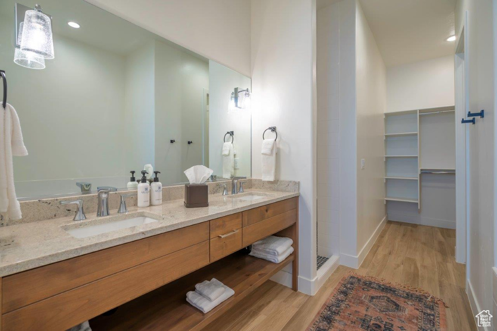 Full bathroom with wood finished floors, double vanity, baseboards, recessed lighting, and walk in shower