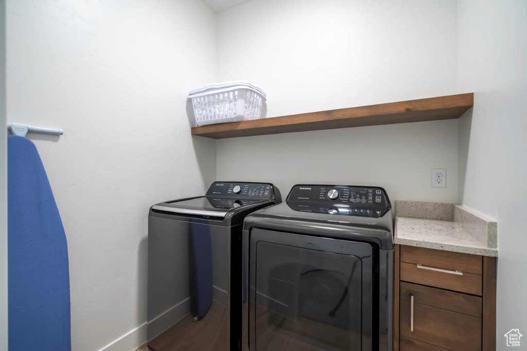 Washroom with washer and dryer, baseboards, and wood finished floors