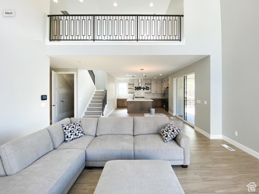 Living area with healthy amount of natural light, a towering ceiling, stairway, recessed lighting, and baseboards