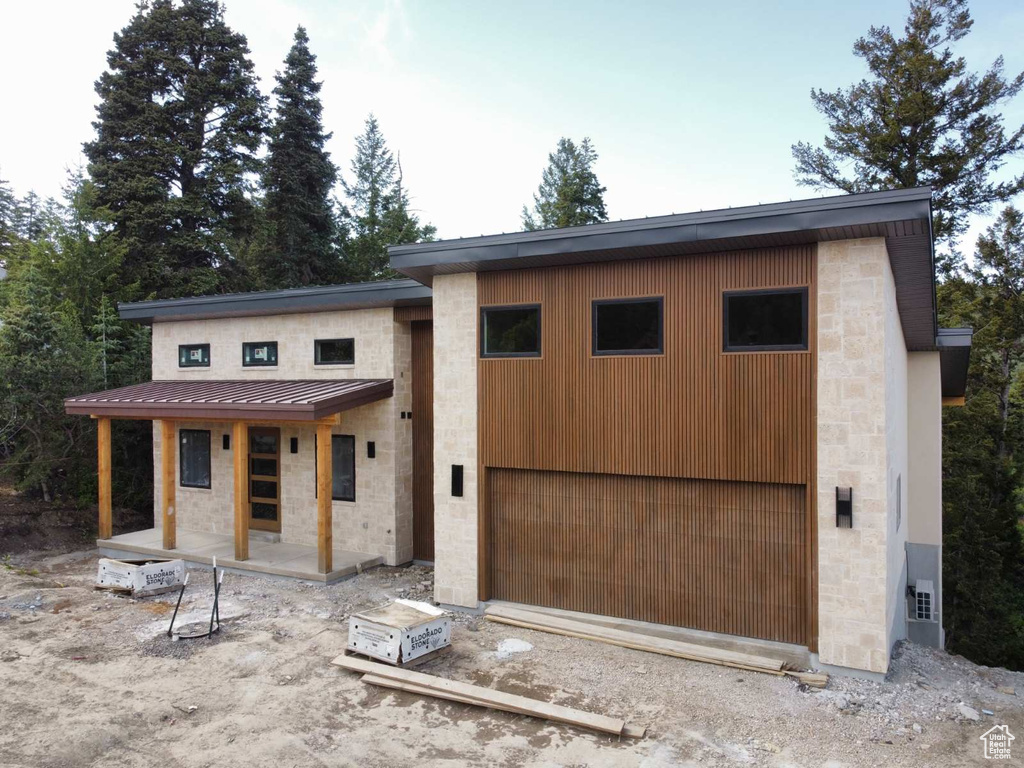 View of front of house featuring stone siding, a standing seam roof, dirt driveway, and metal roof