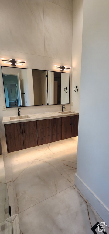 Full bathroom with marble finish floors, baseboards, and double vanity