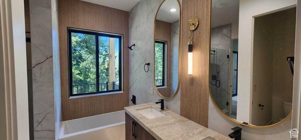 Bathroom with a marble finish shower, double vanity, and a tub