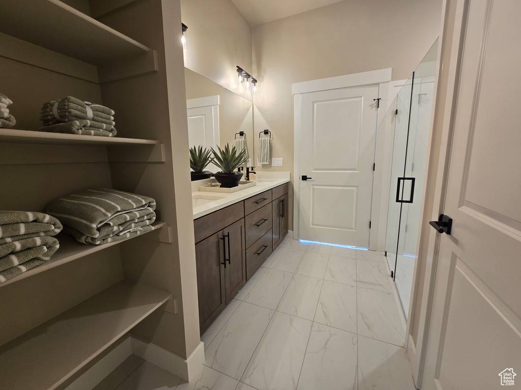 Bathroom with marble finish floors, double vanity, a shower stall, and baseboards