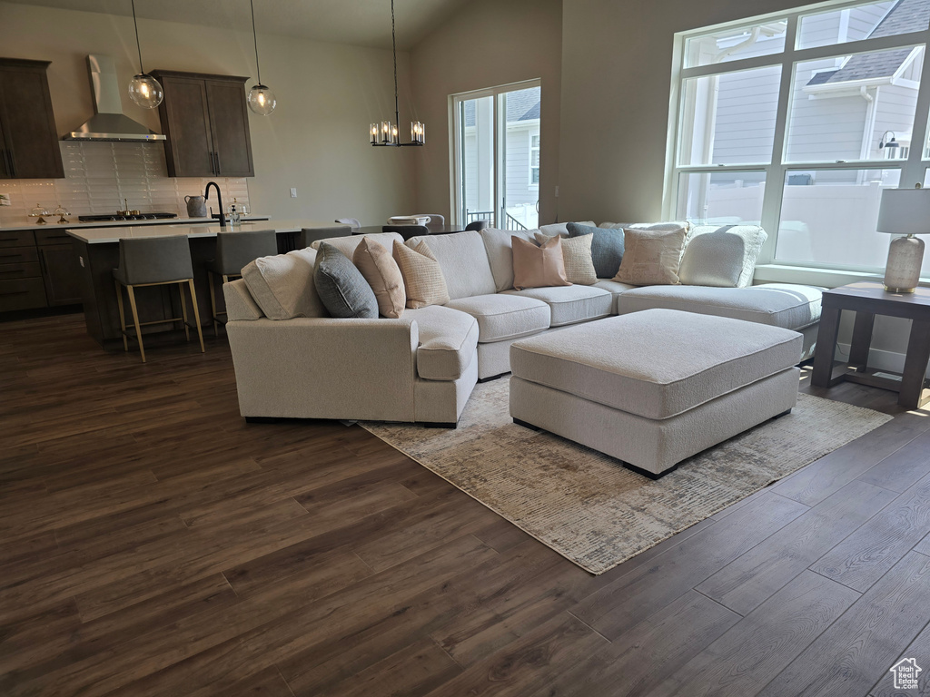 Living area with a chandelier, dark wood finished floors, and vaulted ceiling