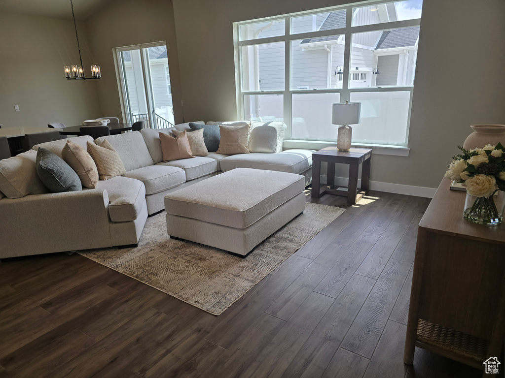 Living room featuring a chandelier, dark wood-style flooring, and baseboards