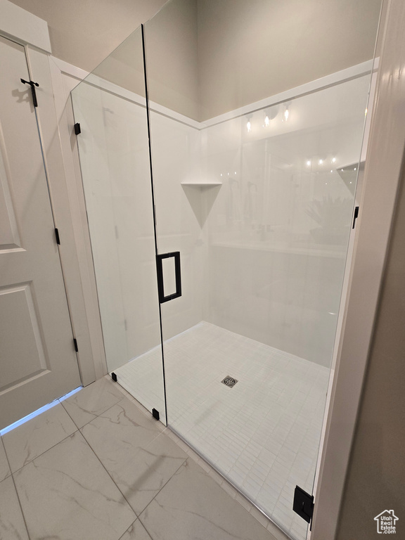 Bathroom with marble look tile flooring and a stall shower