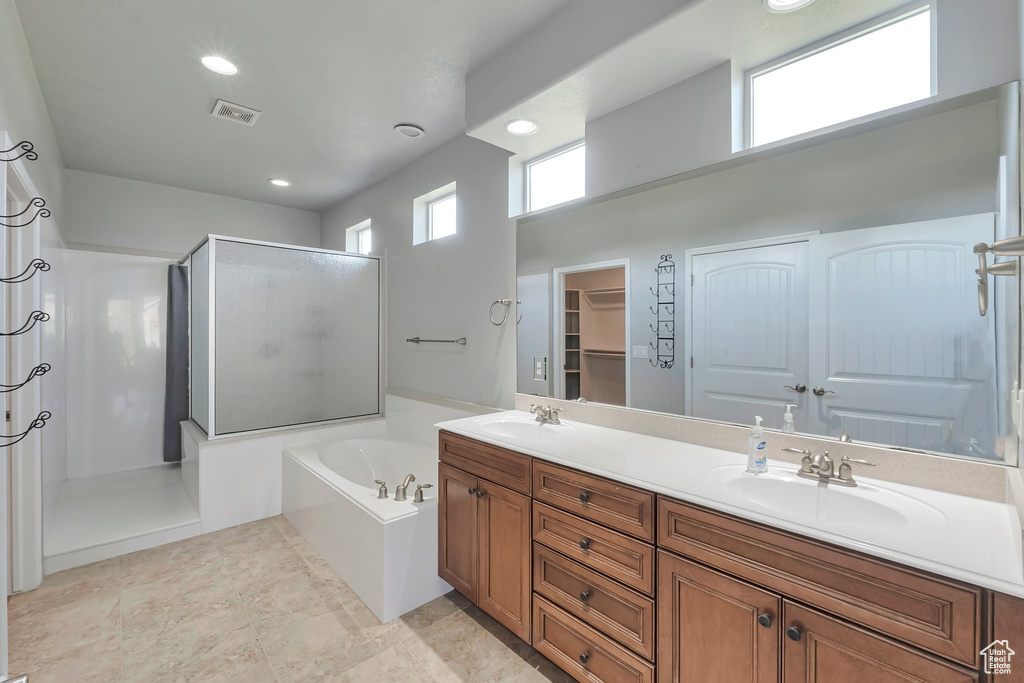 Bathroom with a stall shower, a bath, double vanity, and recessed lighting