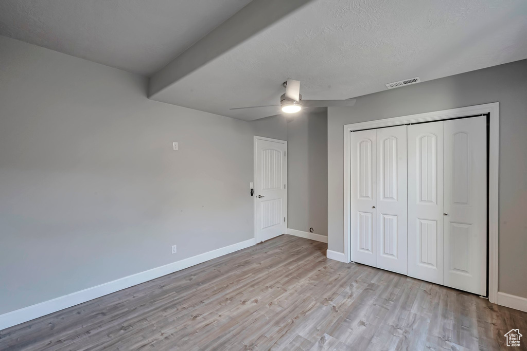Unfurnished bedroom featuring wood finished floors, baseboards, a closet, a ceiling fan, and a textured ceiling