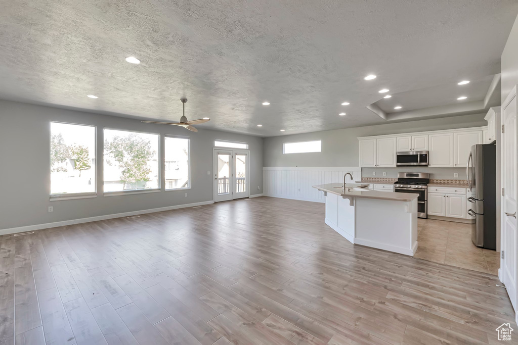 Kitchen featuring stainless steel appliances, open floor plan, recessed lighting, white cabinets, and wainscoting