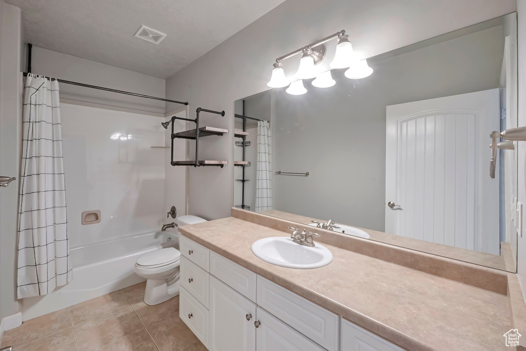 Bathroom featuring vanity, shower / tub combo, toilet, and tile patterned floors