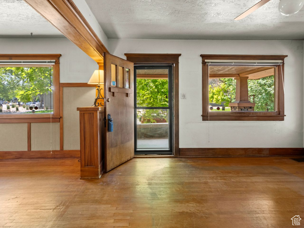 Foyer entrance featuring wood-type flooring, a textured ceiling, a ceiling fan, and baseboards