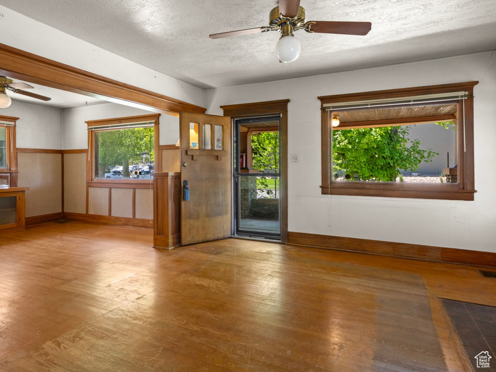 Entryway with ceiling fan, wood finished floors, baseboards, and a textured ceiling