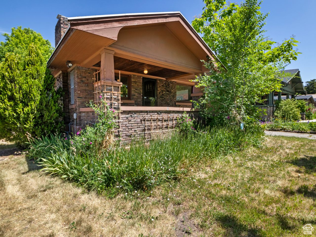 View of front of property with a chimney, covered porch, and brick siding