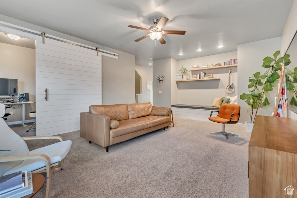 Living room with a barn door, ceiling fan, and carpet floors