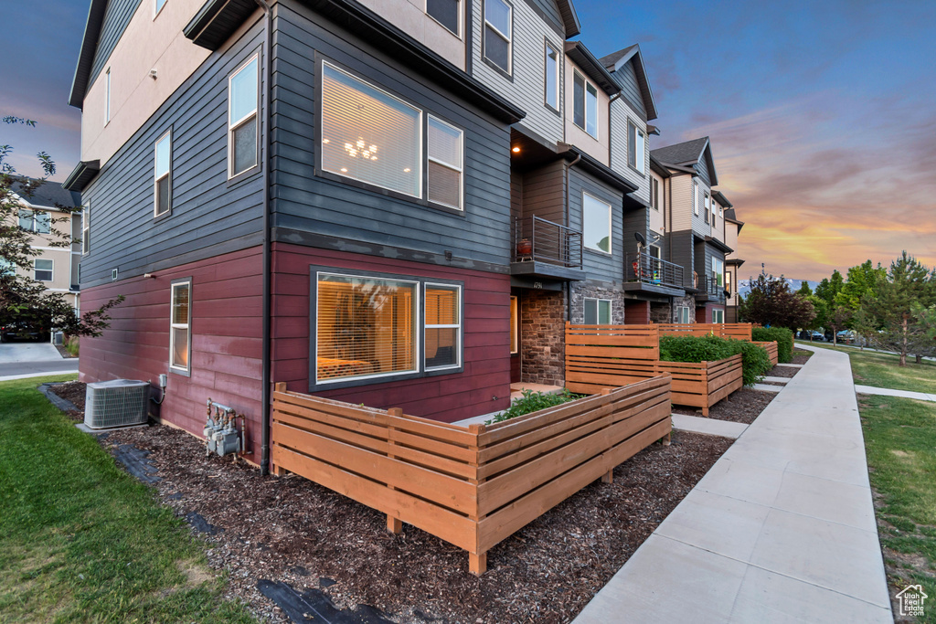View of property exterior with a vegetable garden, cooling unit, a residential view, and stone siding