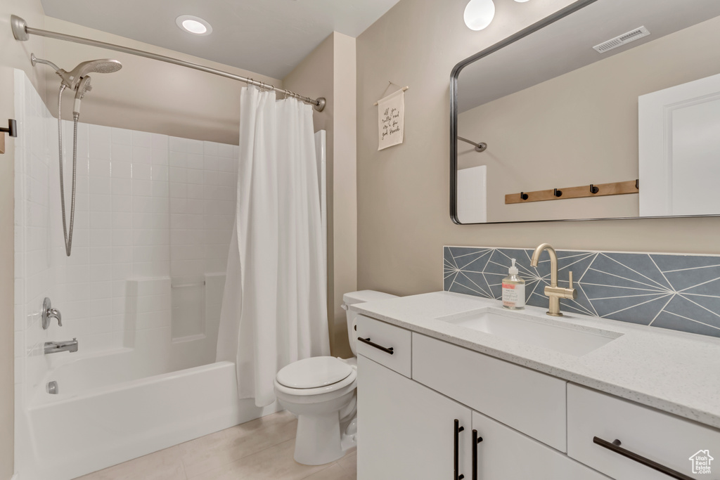 Full bathroom with vanity, shower / bath combo with shower curtain, toilet, and backsplash