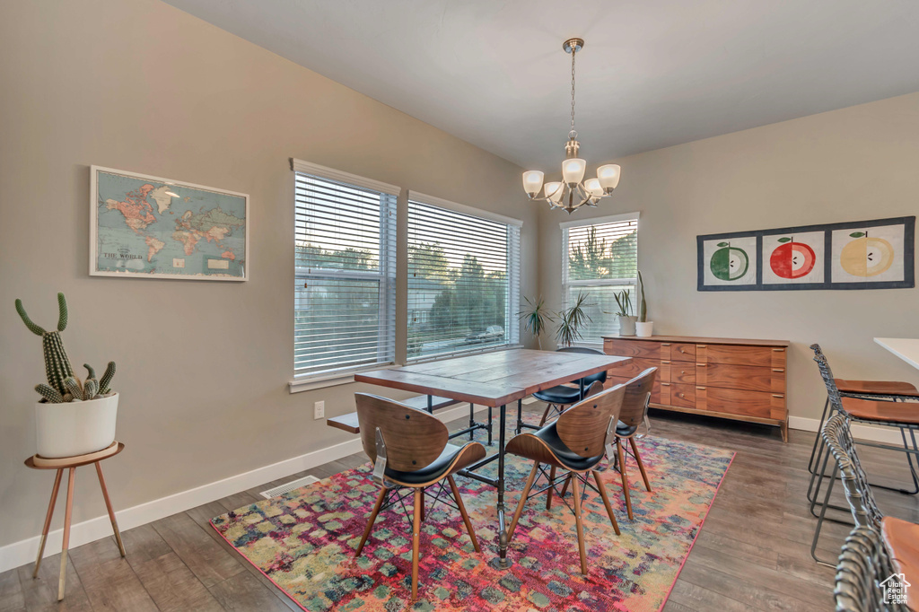 Dining space with a chandelier, wood finished floors, and baseboards