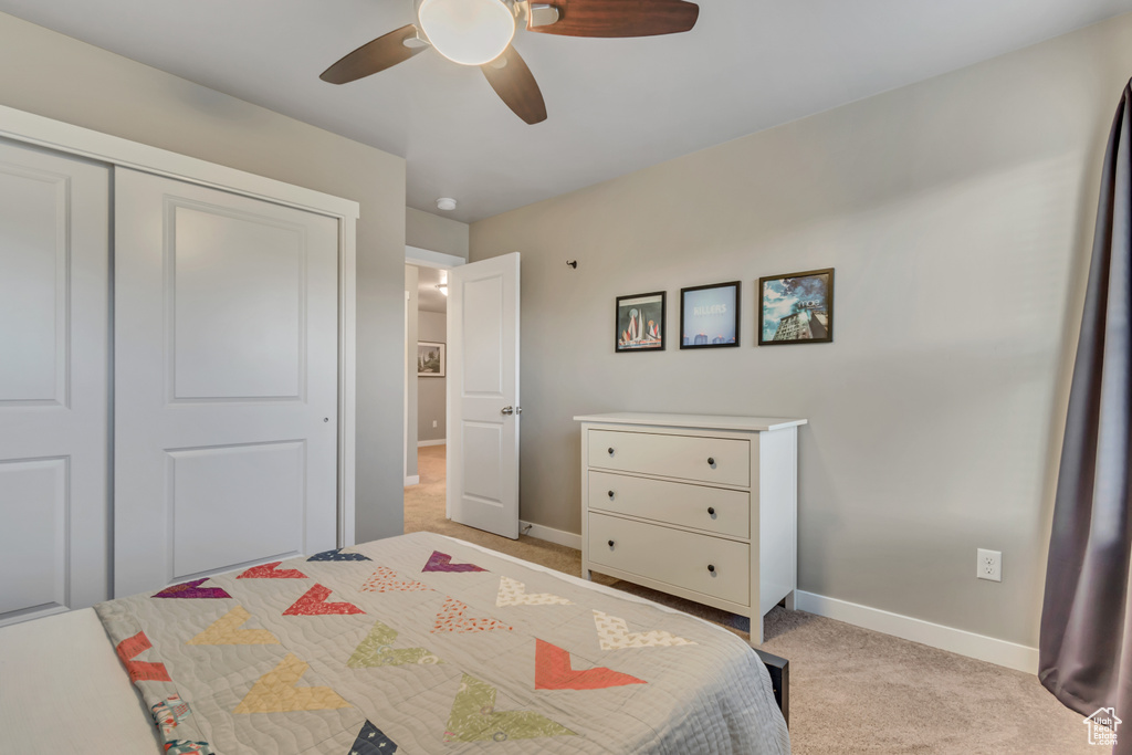 Bedroom with light carpet, baseboards, a closet, and a ceiling fan