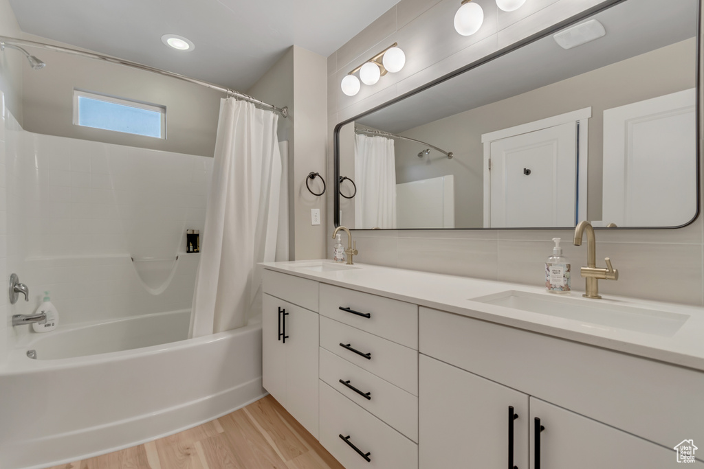 Full bathroom featuring shower / tub combo, double vanity, and wood finished floors