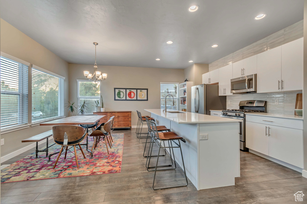 Kitchen featuring stainless steel appliances, a sink, light countertops, a breakfast bar, and recessed lighting