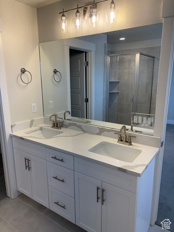 Full bathroom with double vanity, a stall shower, and tile patterned flooring