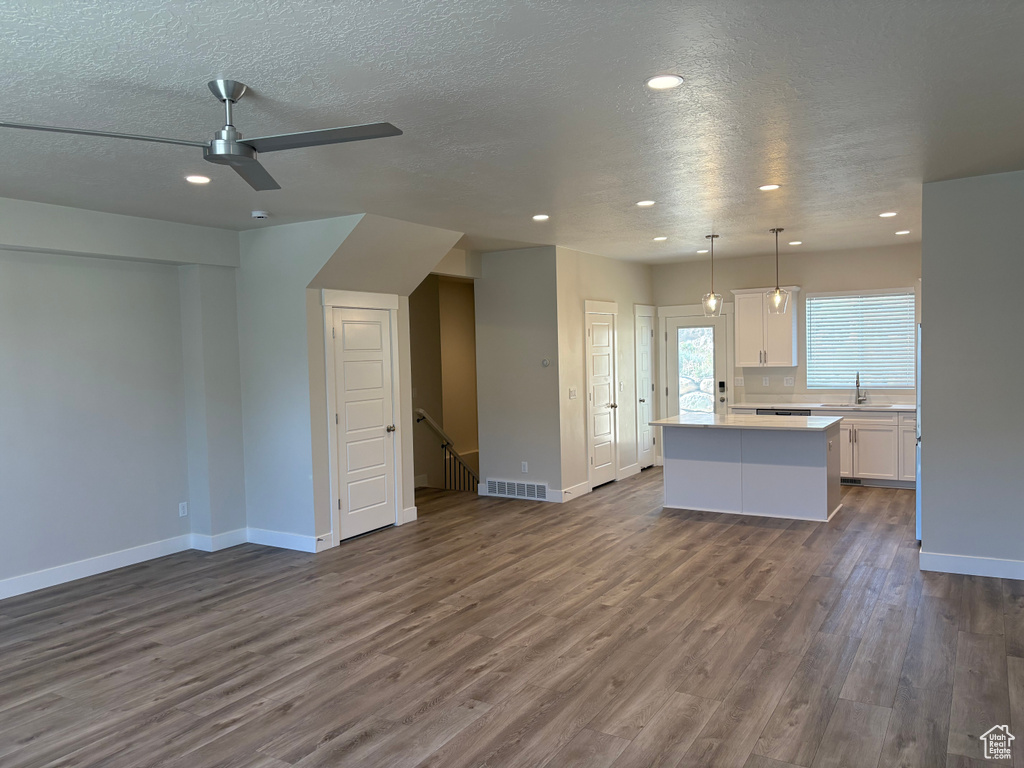 Unfurnished living room with ceiling fan, recessed lighting, a textured ceiling, baseboards, and dark wood-style floors