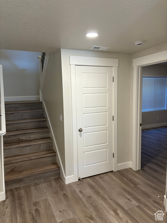 Stairway featuring baseboards, wood finished floors, and recessed lighting