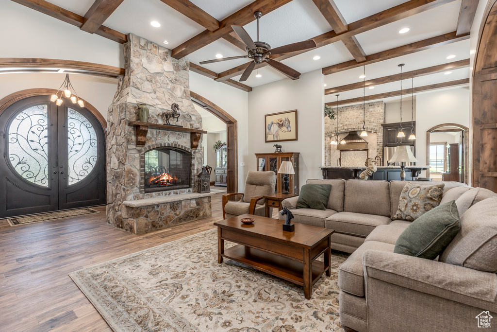 Living area with arched walkways, french doors, wood finished floors, beamed ceiling, and ceiling fan