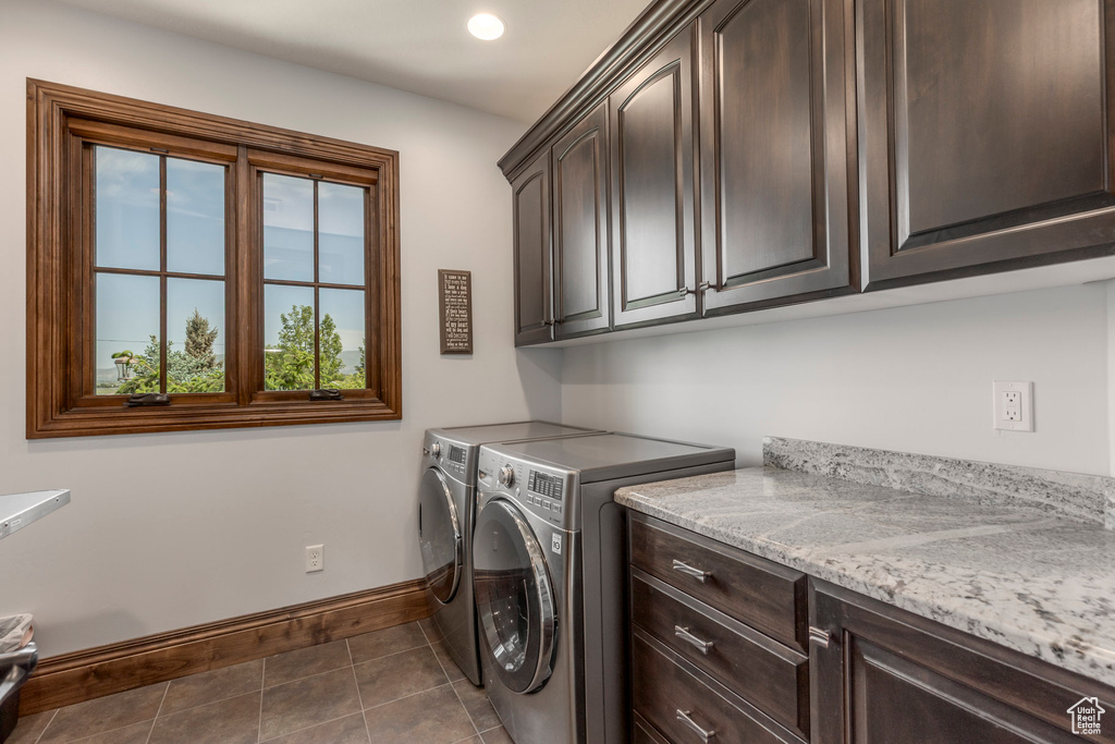 Laundry room with cabinet space, washer and dryer, baseboards, and tile patterned floors