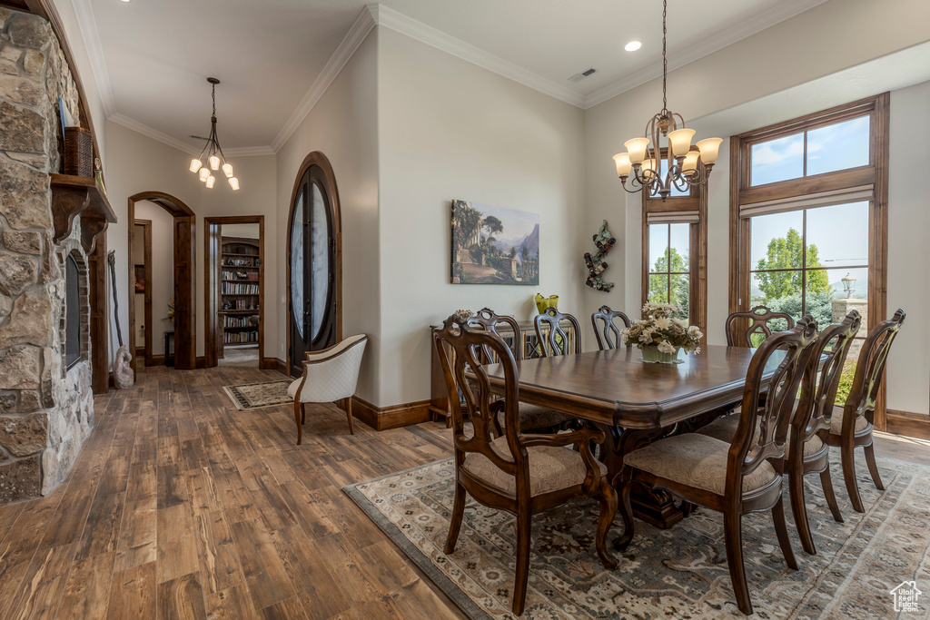Dining area with a chandelier, arched walkways, wood-type flooring, baseboards, and recessed lighting