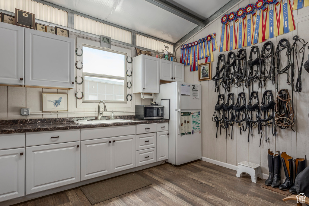Kitchen with a sink, stainless steel microwave, freestanding refrigerator, and white cabinets