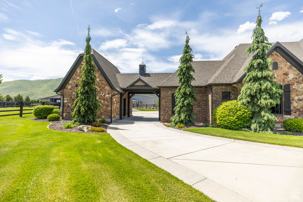 View of front of property featuring brick siding, concrete driveway, a shingled roof, and a mountain view
