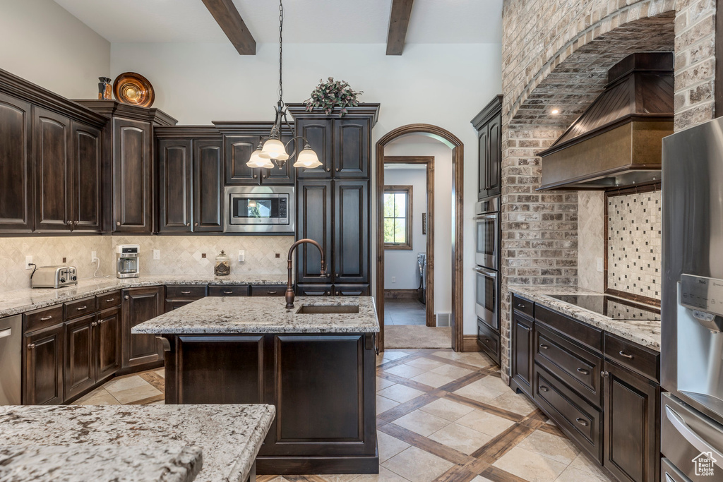 Kitchen featuring stainless steel appliances, a sink, backsplash, premium range hood, and beam ceiling
