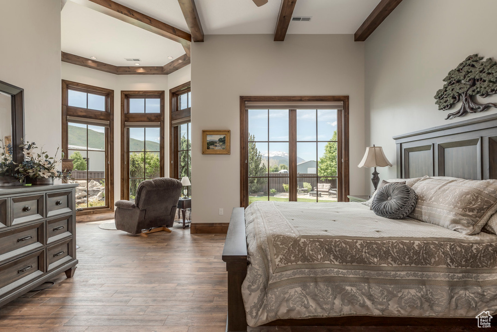 Bedroom featuring beamed ceiling, wood-type flooring, and baseboards