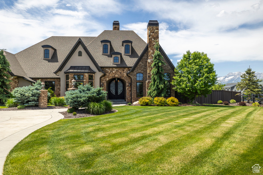 French country home with a chimney, french doors, stone siding, stucco siding, and roof with shingles