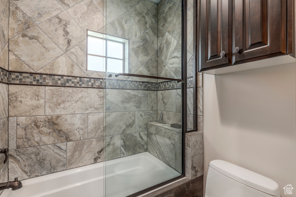 Full bathroom featuring toilet and combined bath / shower with glass door