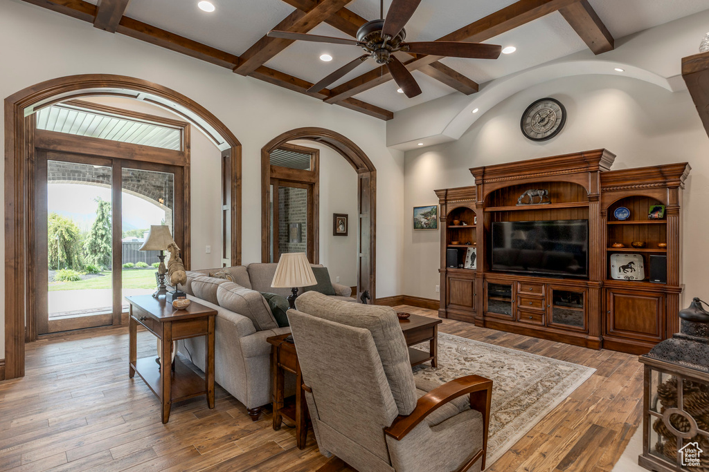 Living room with arched walkways, ceiling fan, light wood-type flooring, beamed ceiling, and recessed lighting
