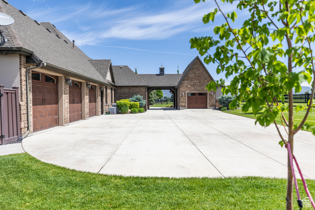 View of side of home with a shingled roof, brick siding, and driveway