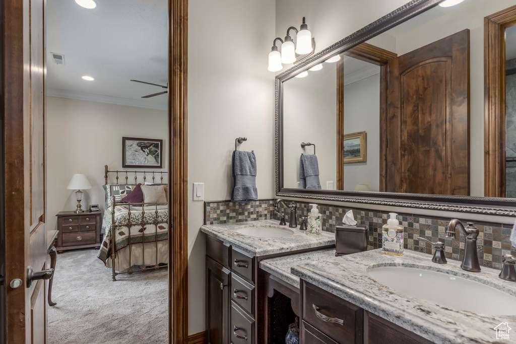 Bathroom with connected bathroom, double vanity, ornamental molding, backsplash, and recessed lighting