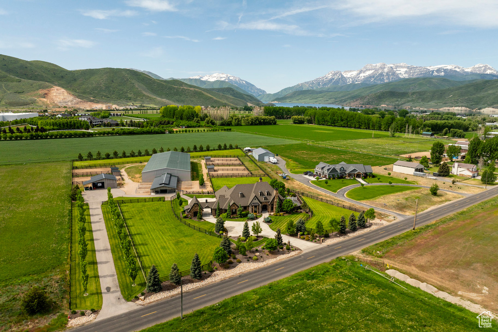 Overview of rural landscape featuring rows of crops and a water and mountain view